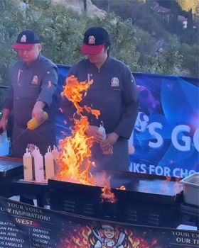 A Love Hibachi chef performs an exciting flame show in front of guests, creating a joyful and unforgettable party moment.